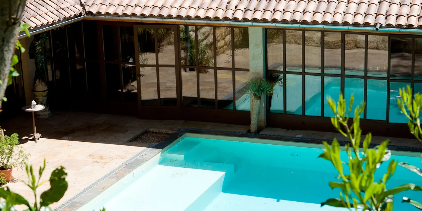 La piscine chauffée du spa, entourée de baies vitrées et de pierres